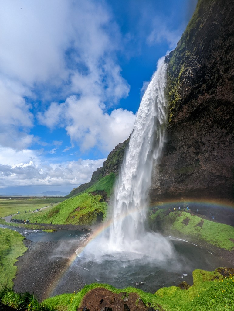 Seljalandsfoss in Iceland on a sunny day with a rainbow